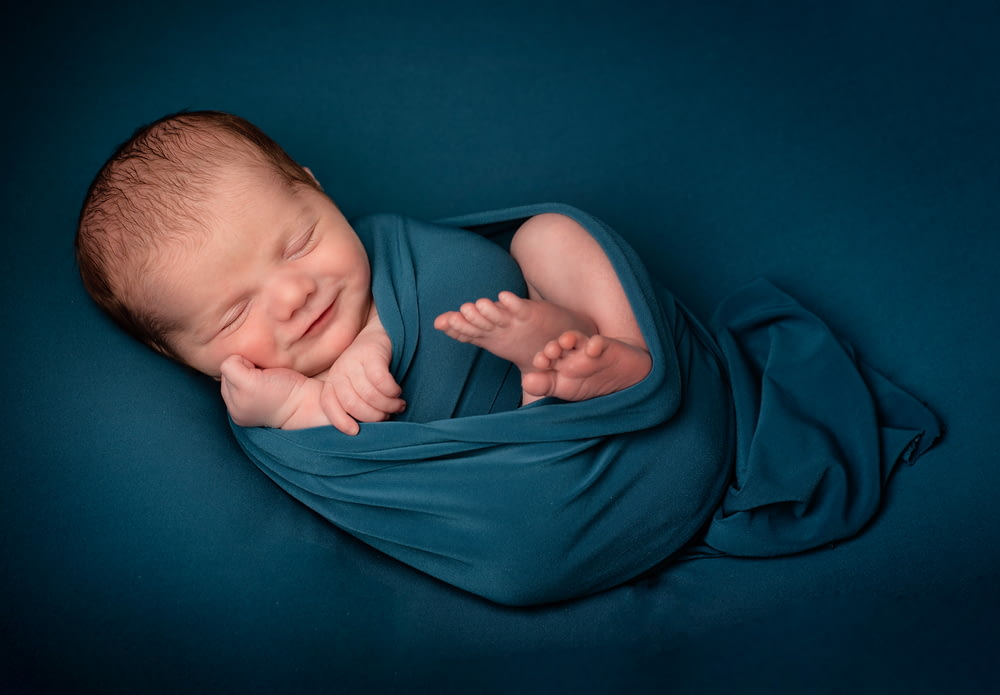 baby lying on blue textile