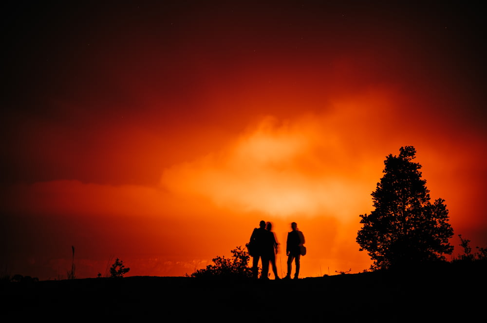 silhouette of 3 men standing on ground during sunset