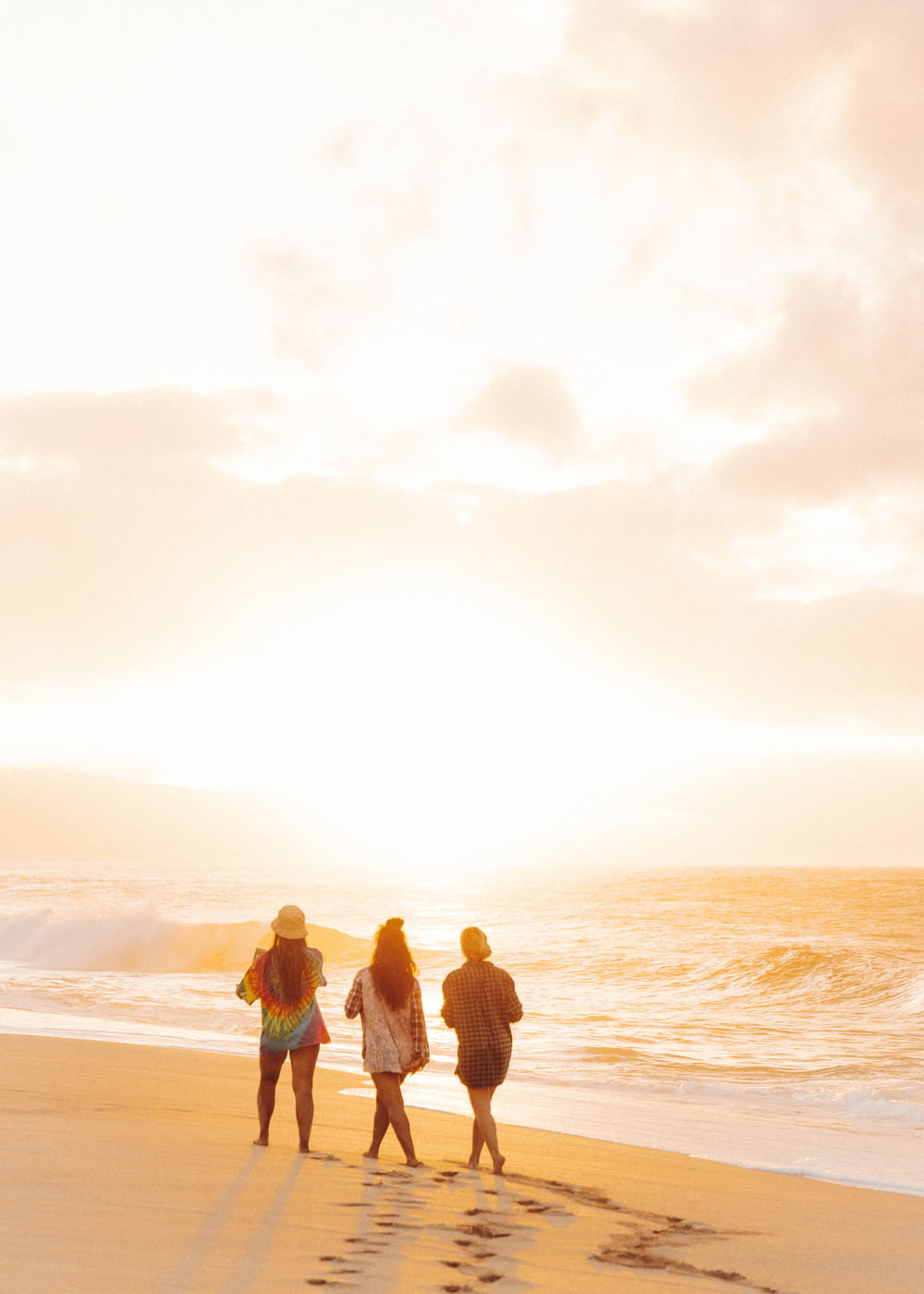 3 women and man standing on beach during sunset