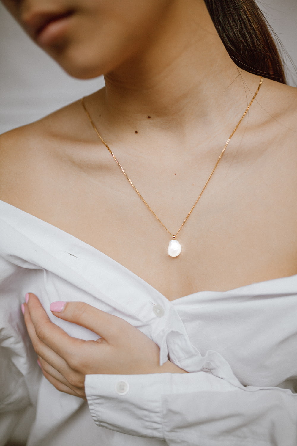 mulher no botão branco para cima camisa vestindo colar de ouro