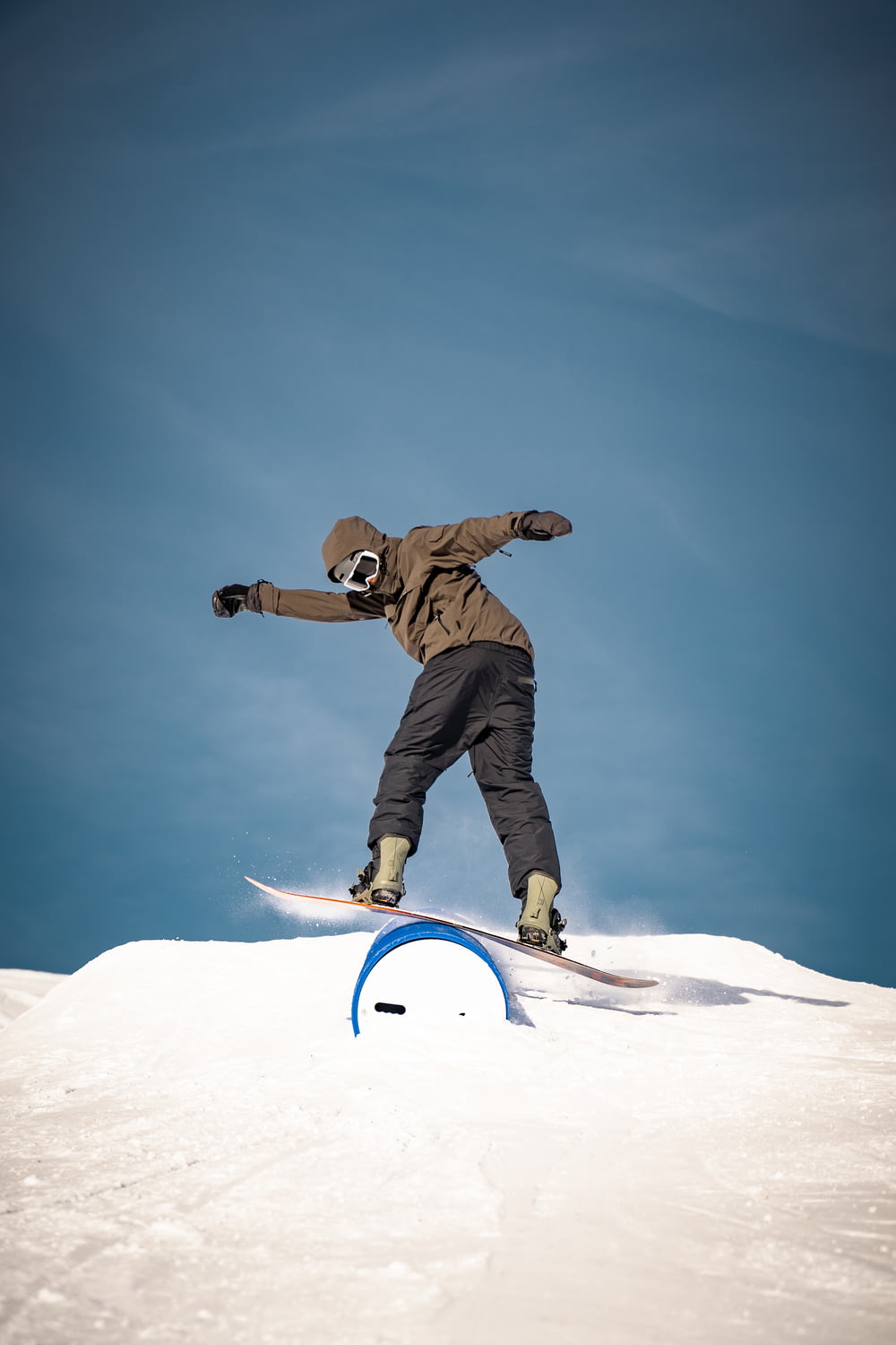man in brown jacket and black pants riding white snowboard during daytime
