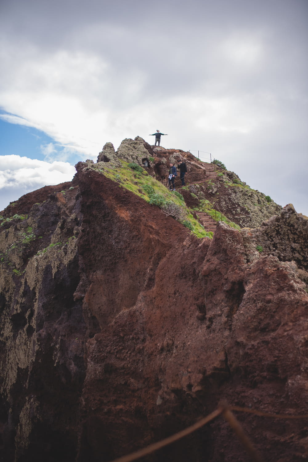 pessoa em pé na formação rochosa marrom sob o céu azul durante o dia