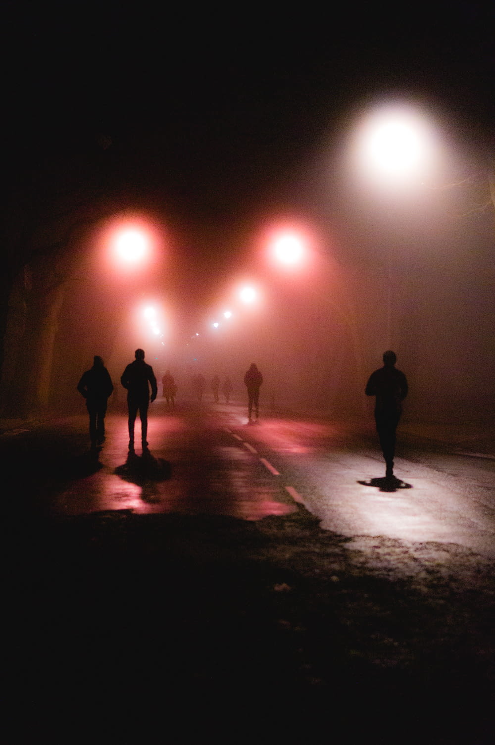 silhouette di persone che camminano sulla strada durante la notte