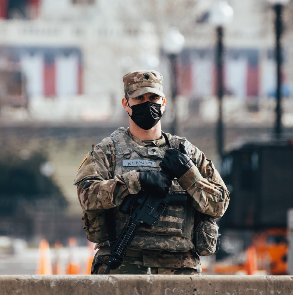 homem no uniforme de camuflagem preto e marrom segurando o rifle