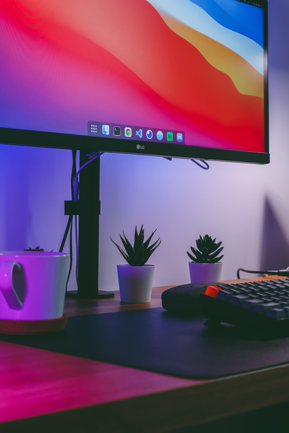 black flat screen computer monitor turned on beside purple ceramic mug