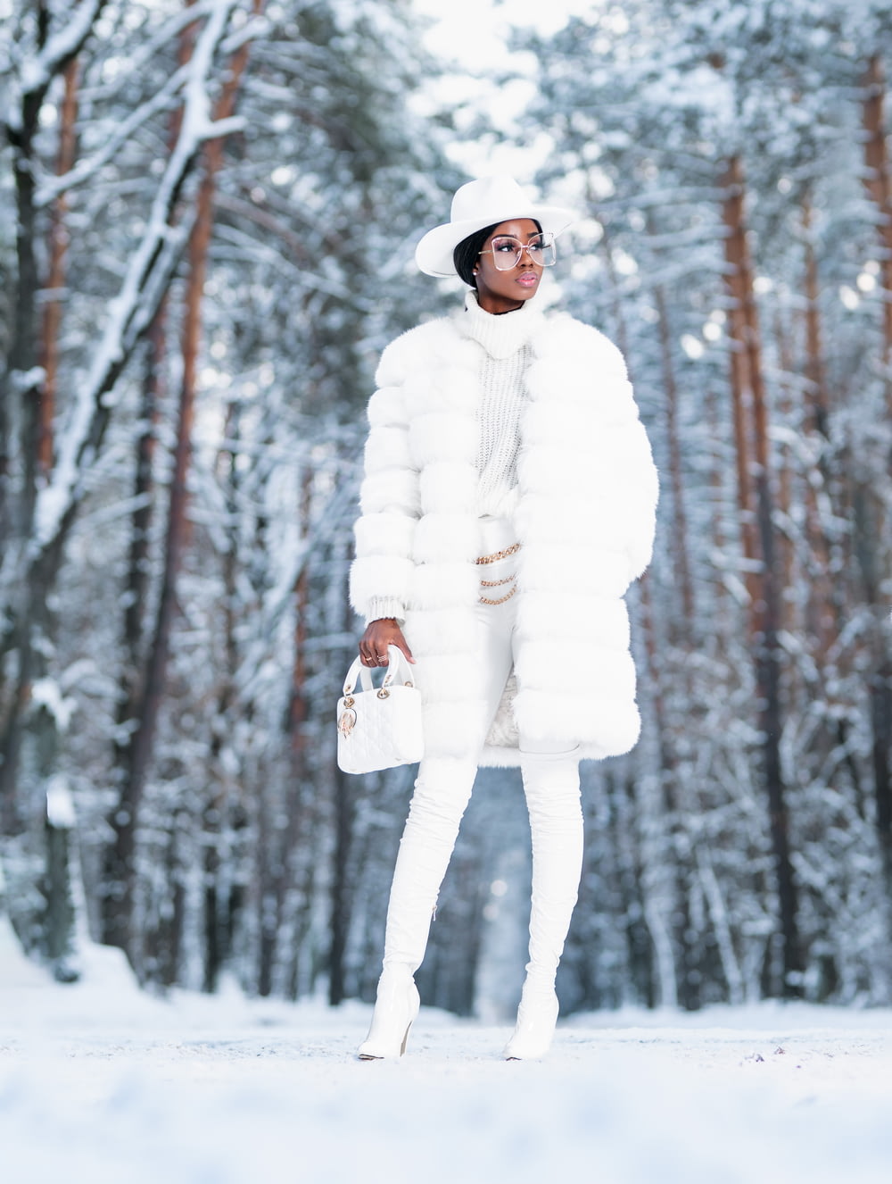 donna in cappotto bianco in piedi su terreno coperto di neve
