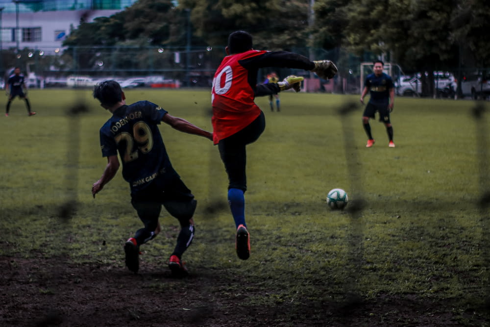 2 men playing soccer on field during daytime