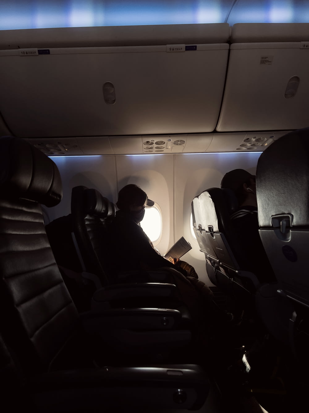 homme en veste noire assis sur un siège d’avion