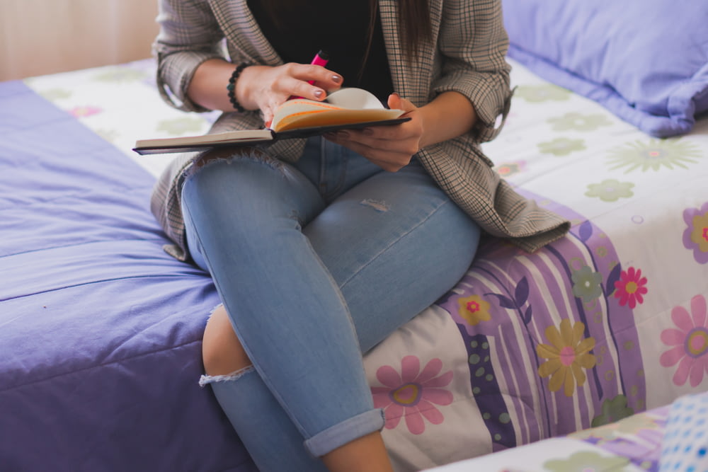 woman in brown cardigan and blue denim jeans sitting on purple and white floral couch