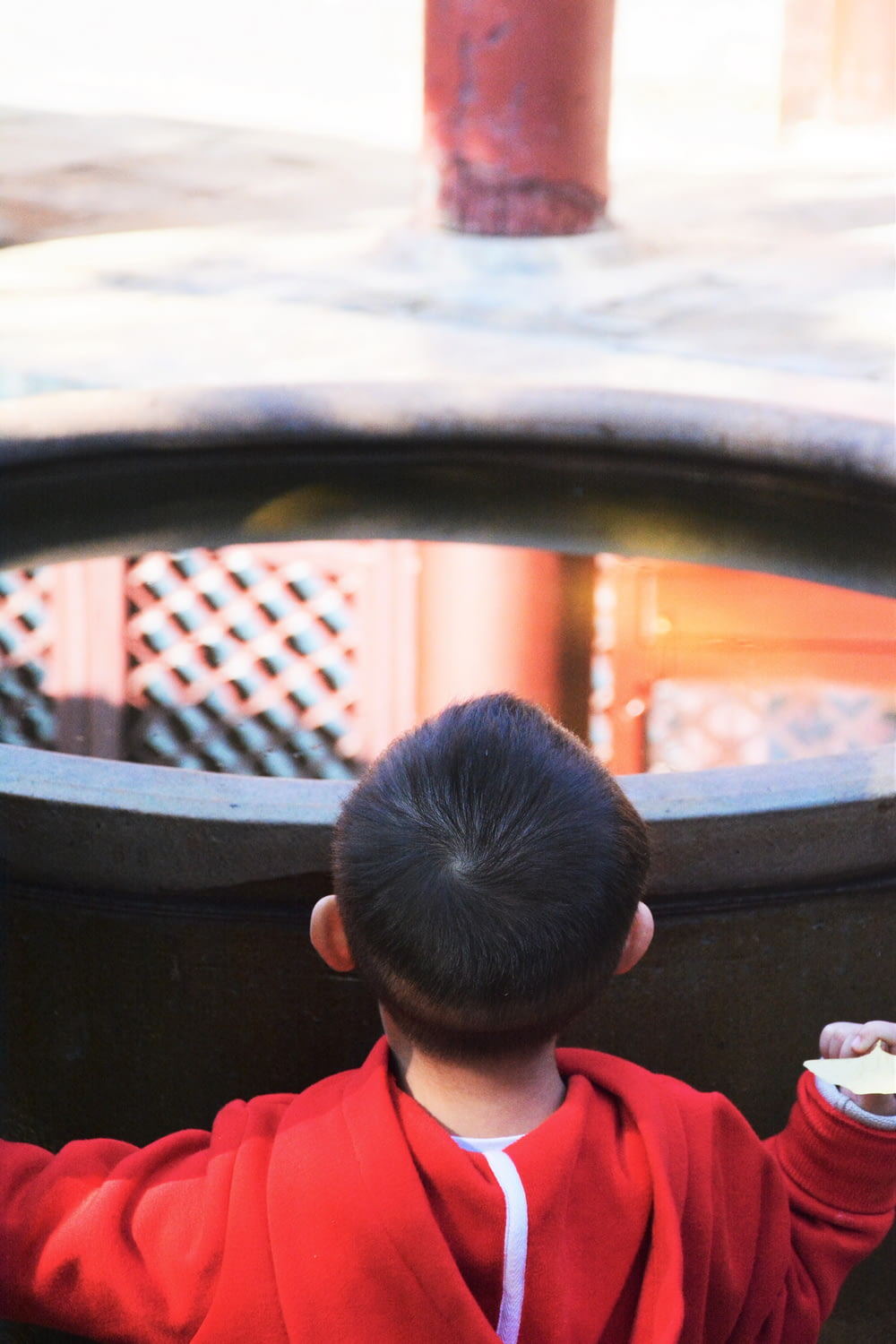 Ein kleiner Junge in einer roten Jacke, der eine weiße Frisbee hält