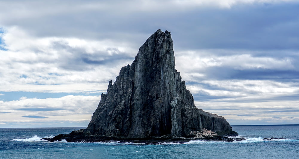 gray rock formation on blue sea under white clouds during daytime