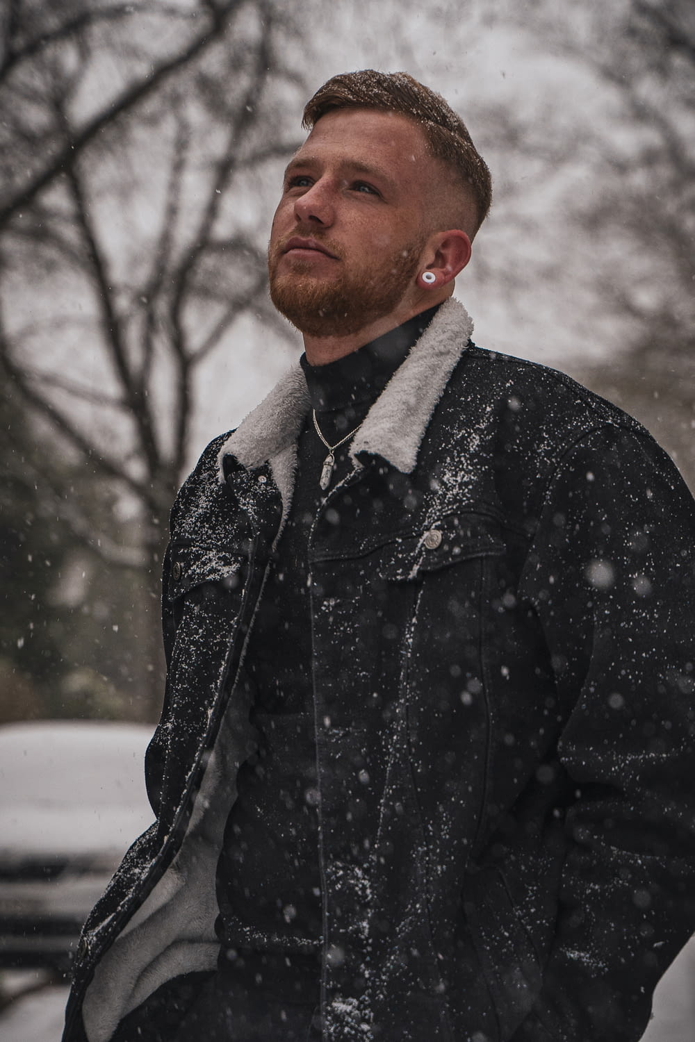 Mann in schwarz-grauer Button-up-Jacke tagsüber auf schneebedecktem Boden
