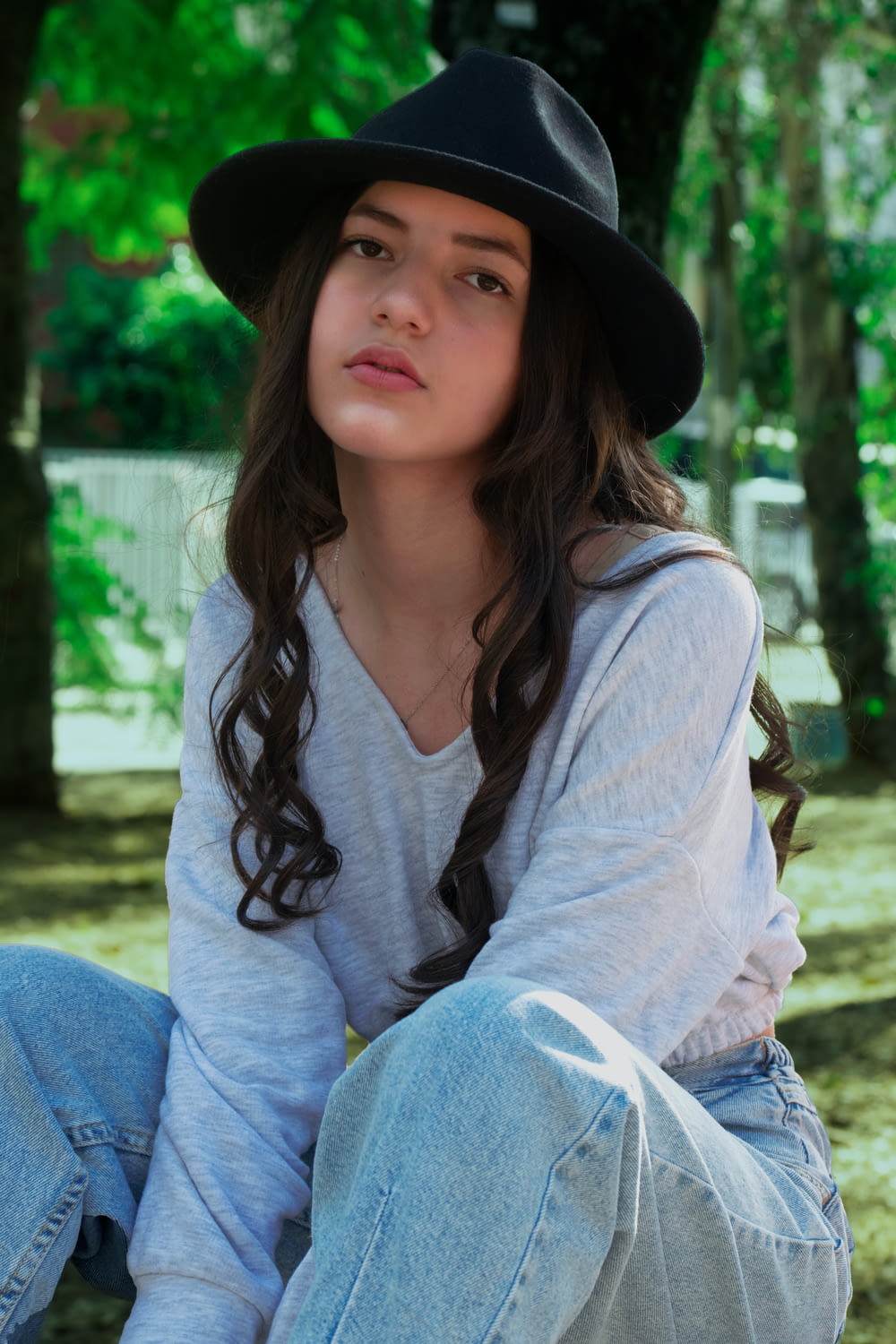 a girl wearing a black hat sitting on the ground