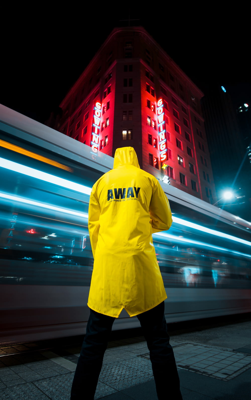 hombre con sudadera con capucha amarilla de pie en la calle durante la noche