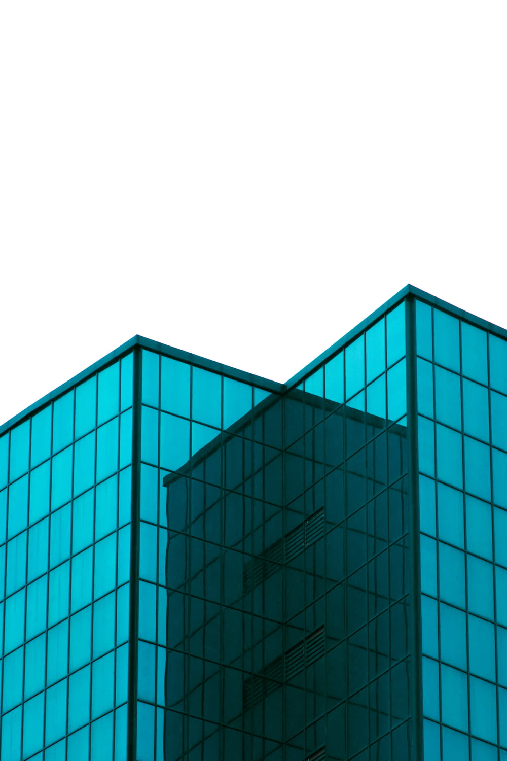 blaues Gebäude mit Glaswänden unter weißem Himmel tagsüber