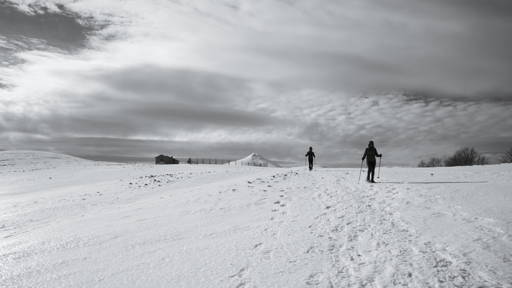 日中の積雪地を歩く2人