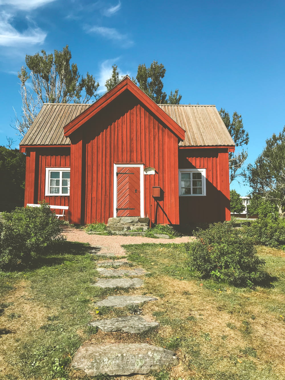 rot-weißes Holzhaus in der Nähe von grünen Bäumen unter blauem Himmel tagsüber