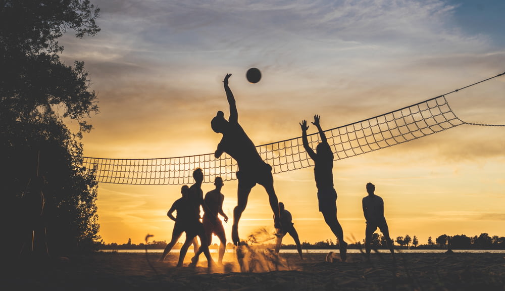 Silueta de la gente jugando al baloncesto durante la puesta del sol