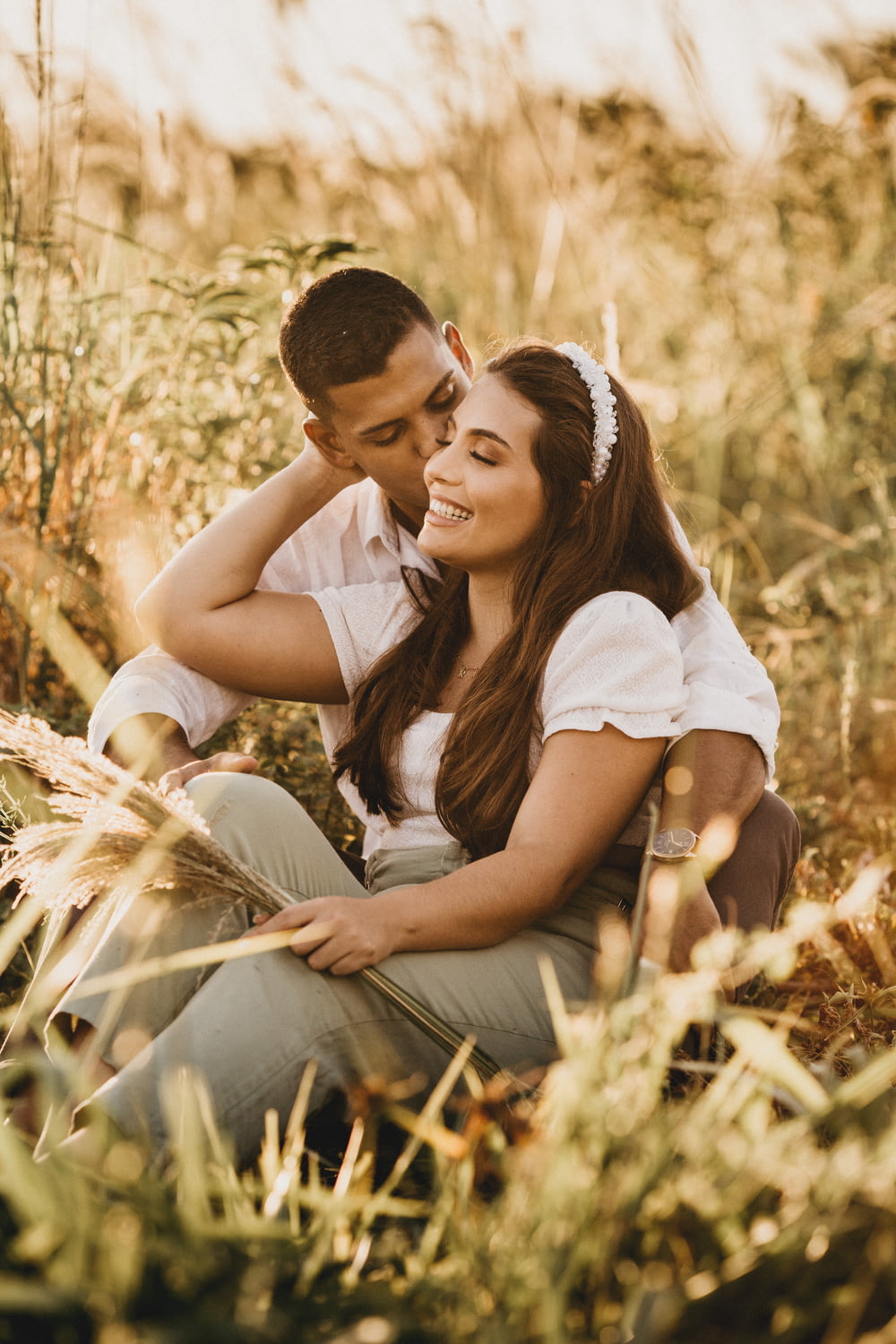 man and woman kissing on brown grass during daytime