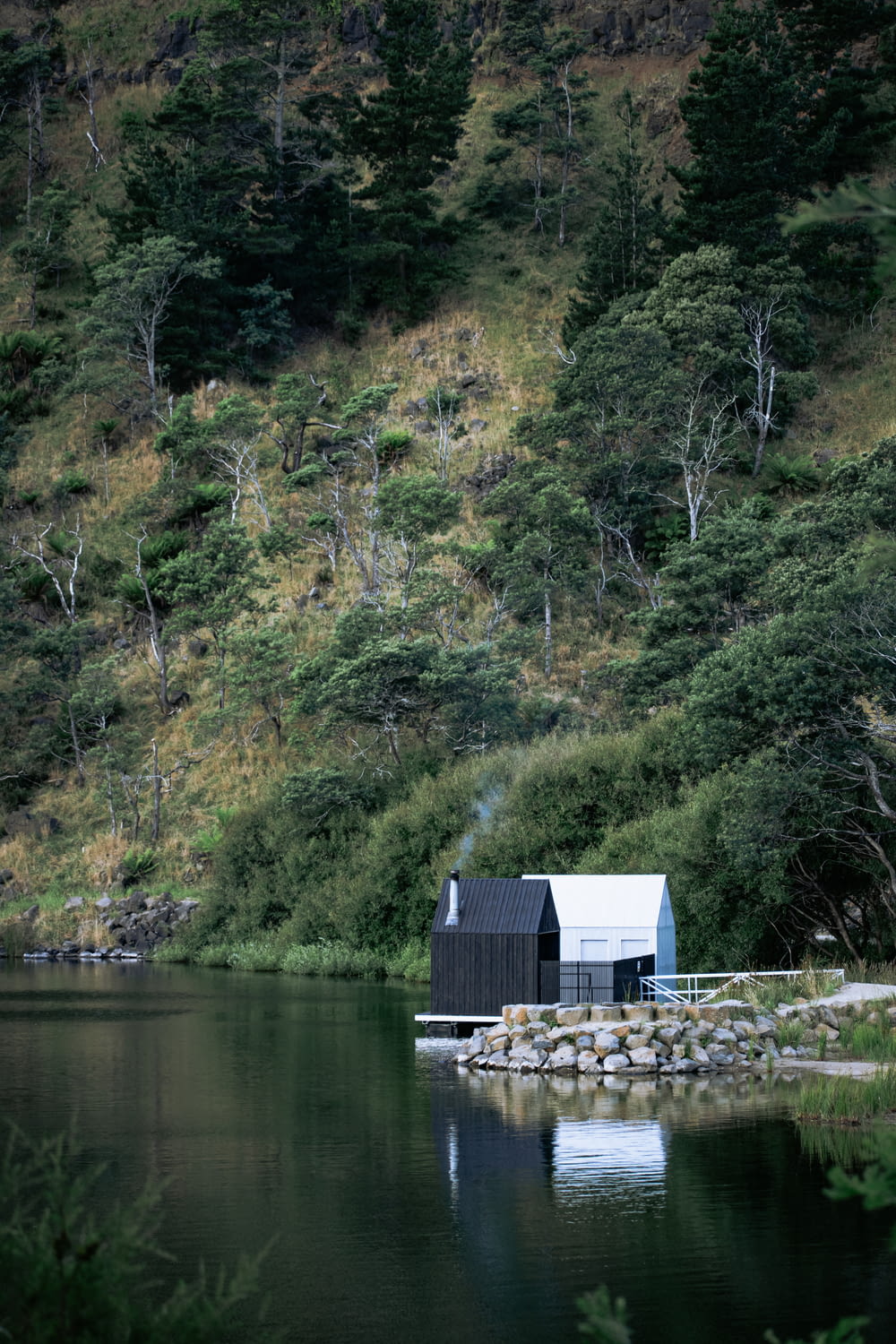 Casa de madera azul y blanca junto a árboles verdes y cuerpo de agua durante el día
