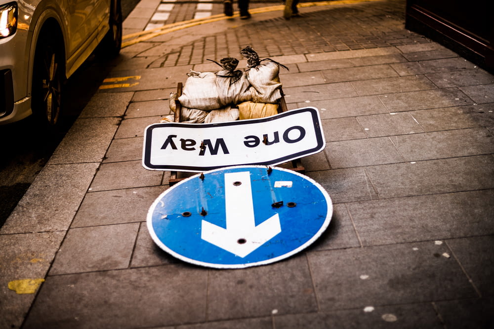 Un letrero azul y blanco sentado al costado de una carretera