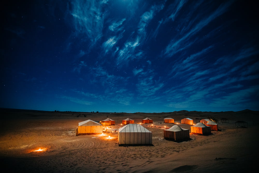 weißes und braunes Zelt auf braunem Feld unter blauem Himmel während der Nacht