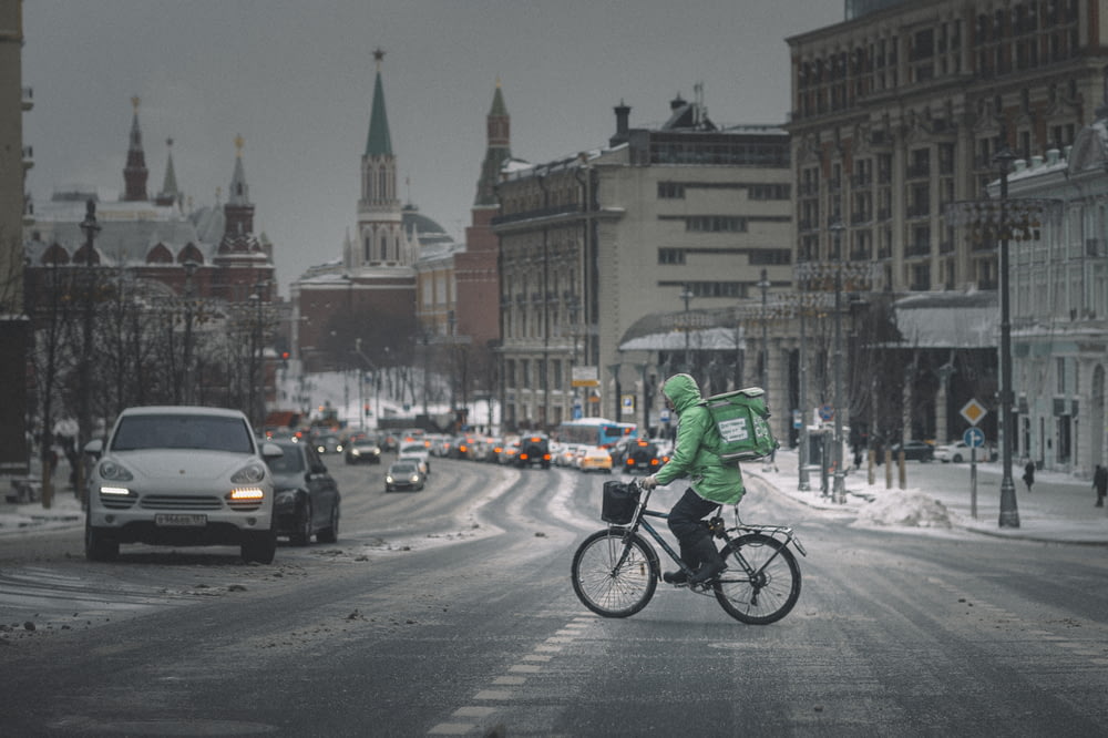 man in green jacket riding bicycle on road during daytime