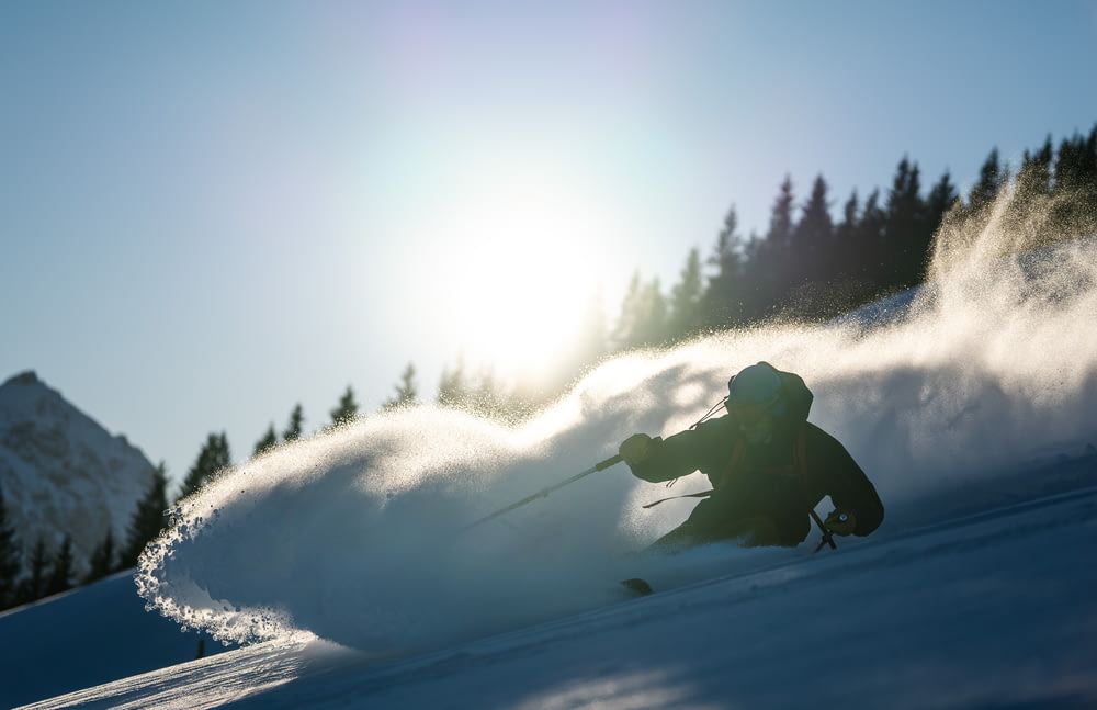 person in black jacket and pants riding on snowboard during daytime