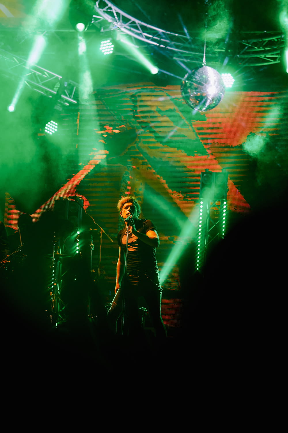 man in black jacket singing on stage
