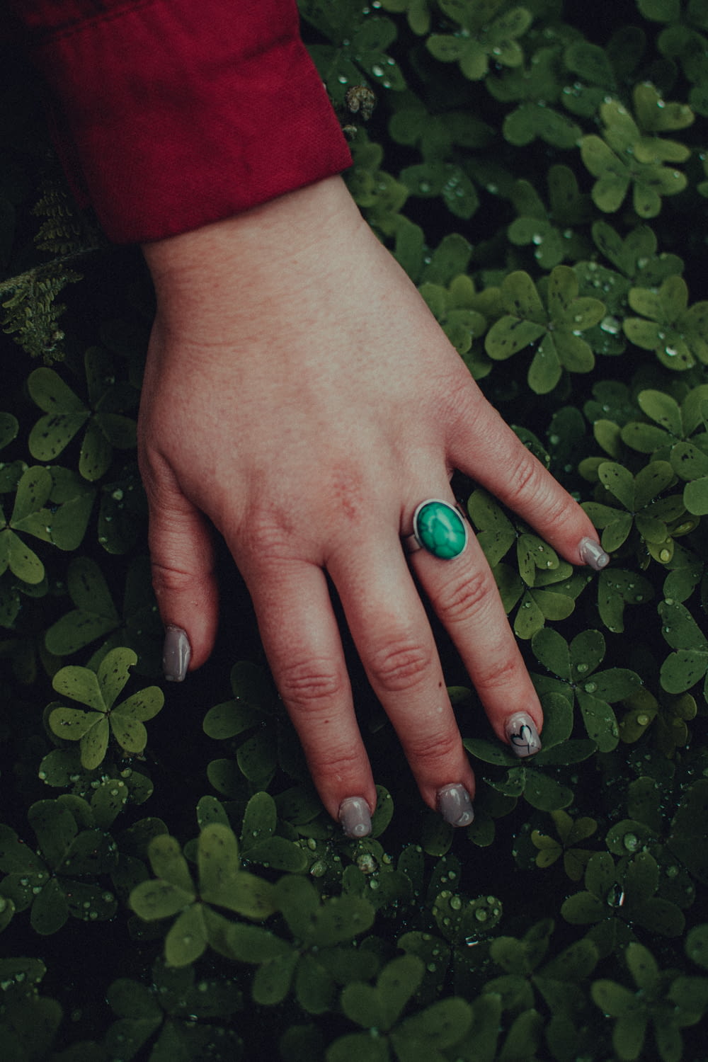 person with green nail polish holding green round ornament