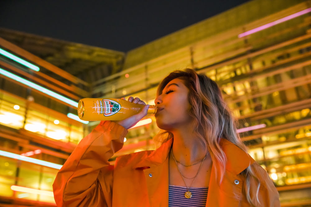 woman in orange blazer drinking from bottle