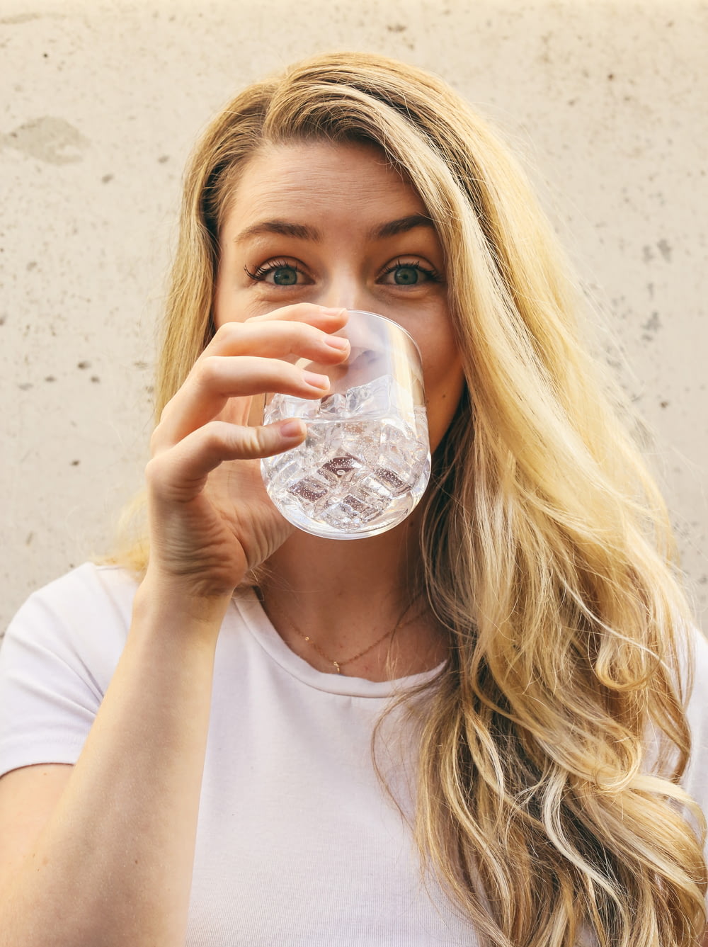 白いクルーネックシャツの女性が水を飲む