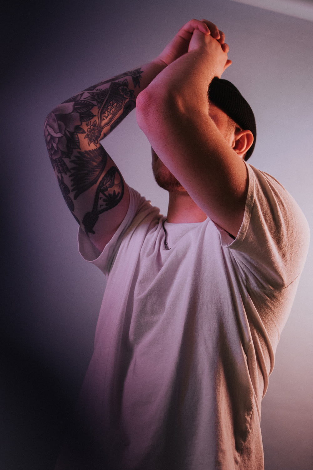 man in white t-shirt with black and red floral tattoo on his right arm