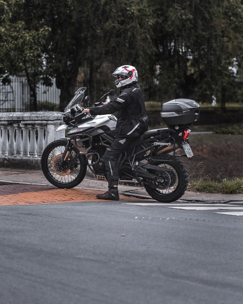 검은 오토바이 헬멧을 쓴 남자가 낮 동안 도로에서 오토바이를 타고