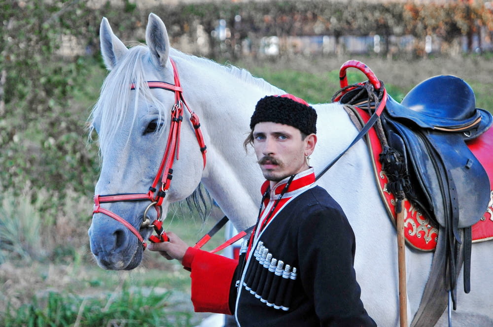 Mann in schwarzer Jacke reitet tagsüber auf weißem Pferd