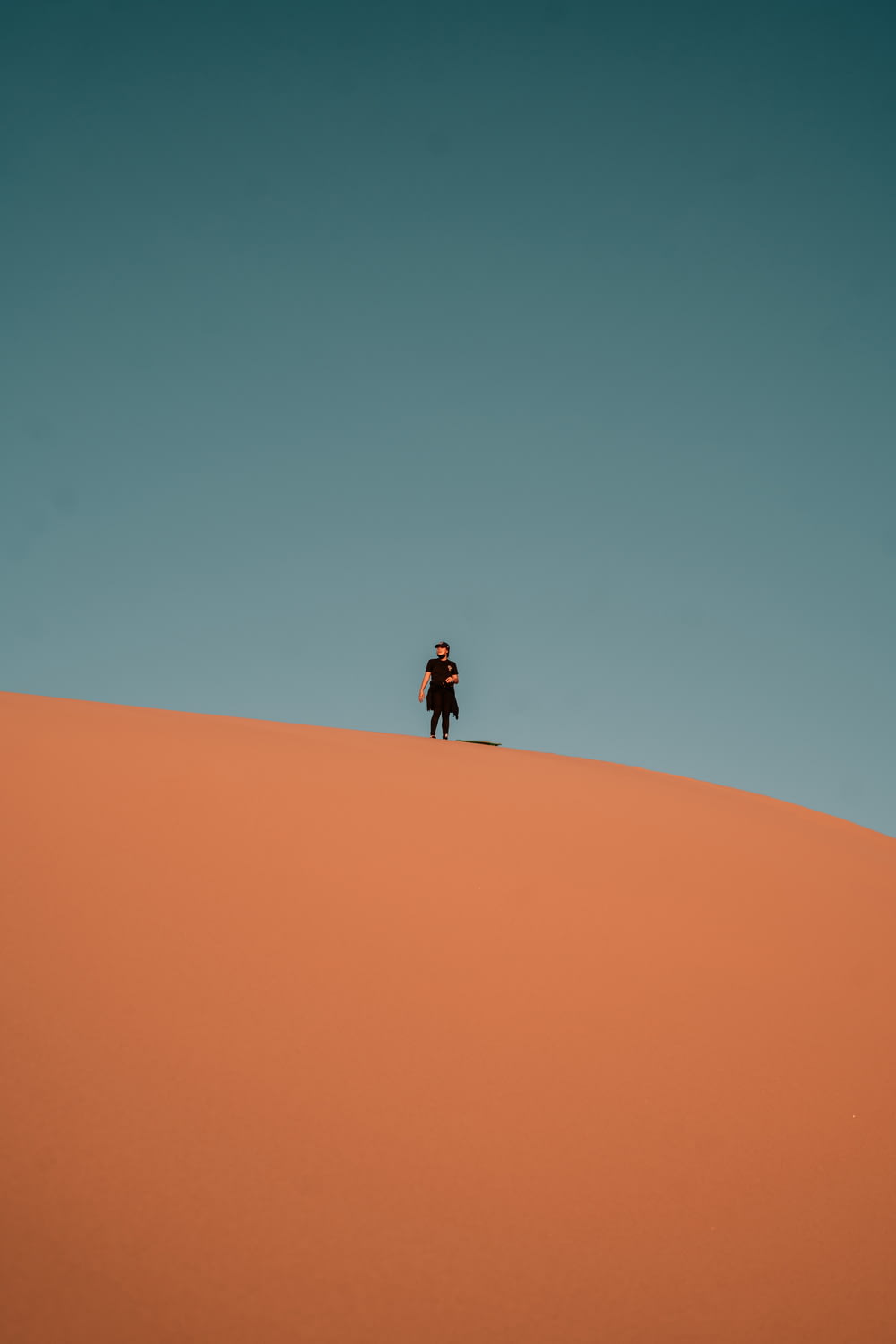 person in black jacket walking on desert during daytime