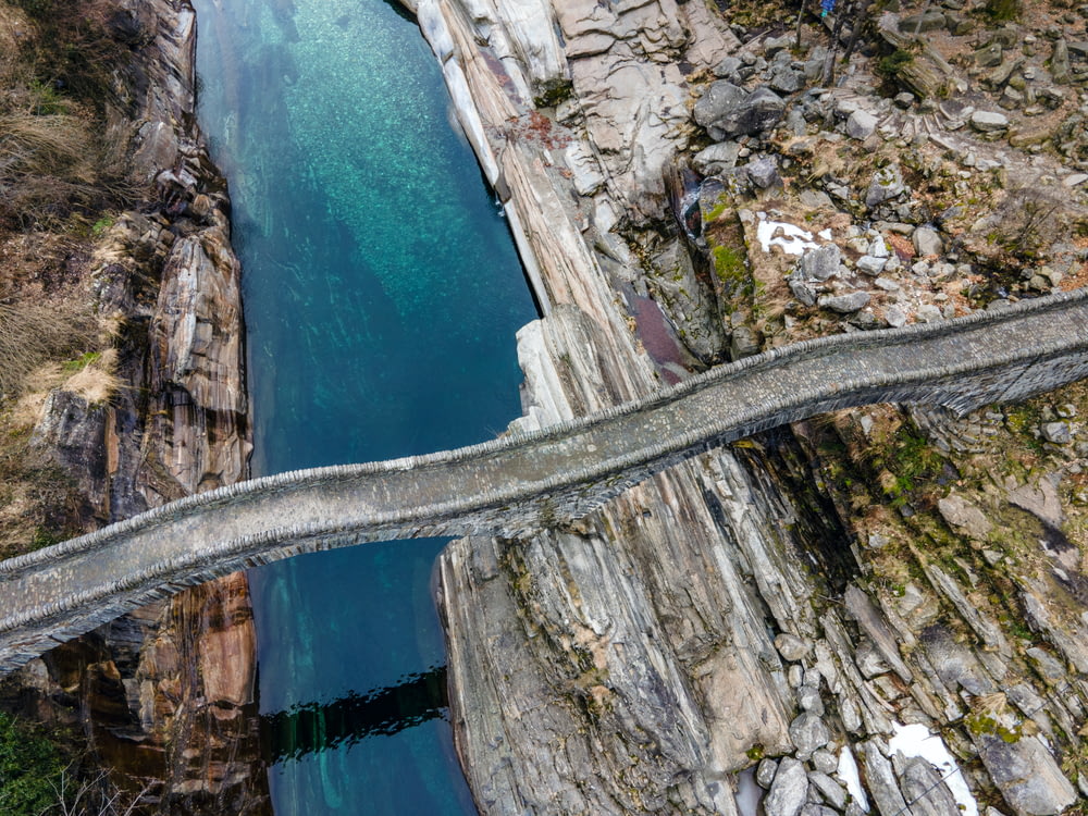 Route en béton gris sur la montagne rocheuse à côté de l’eau bleue