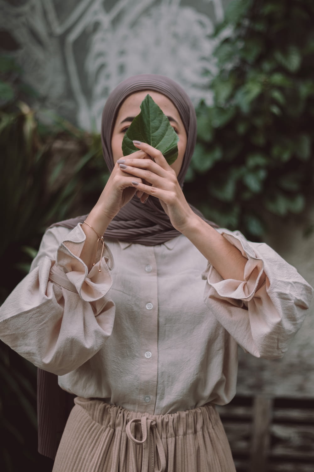 woman in white button up shirt covering her face with white and green textile