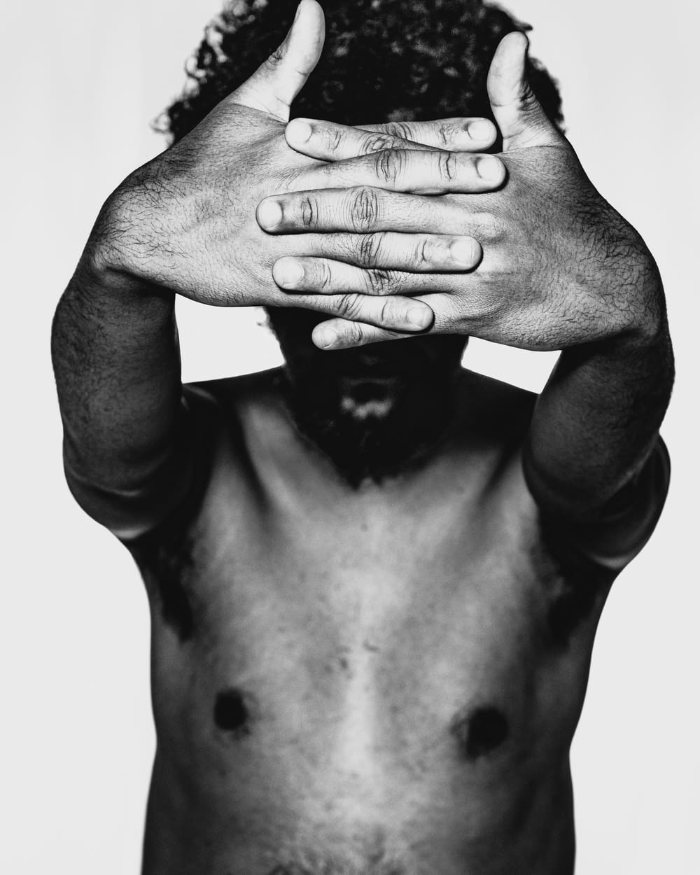 grayscale photo of topless man with tattoo on his right hand