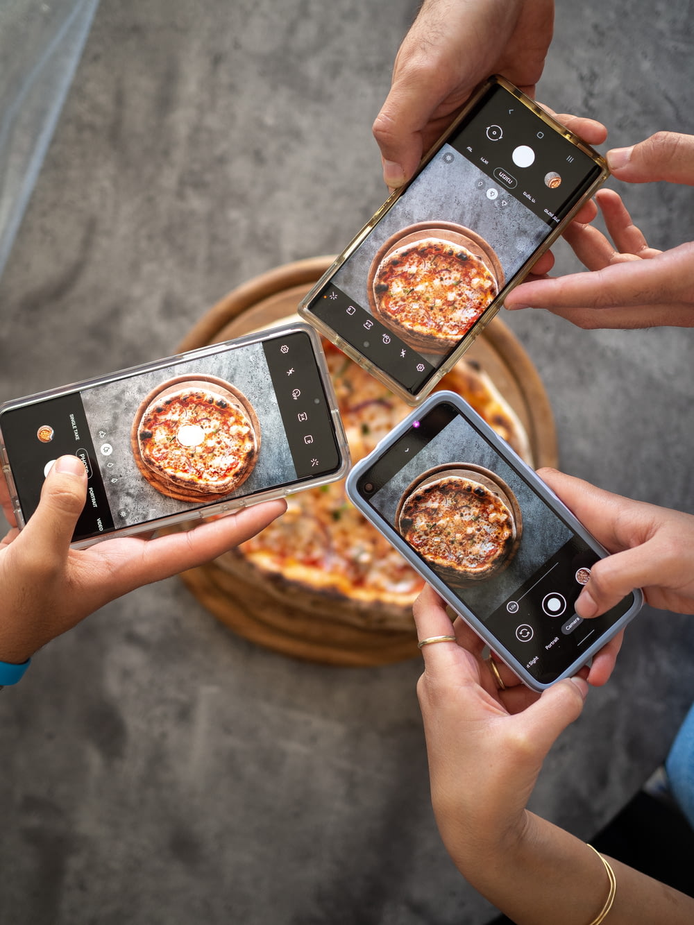 Persona che tiene lo smartphone nero che scatta foto di pizza