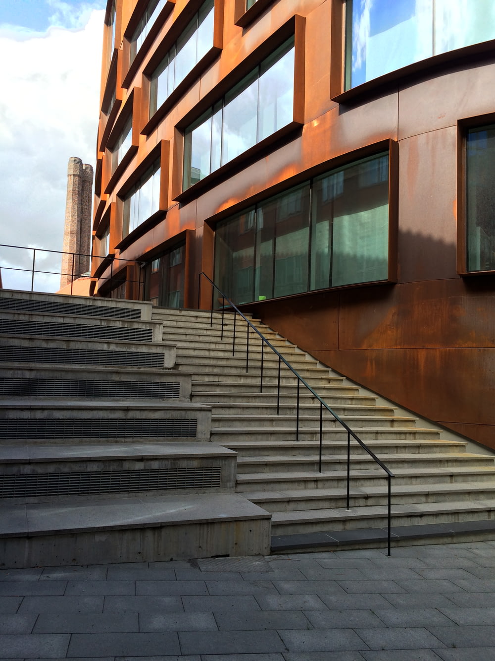 Escalera de hormigón marrón con barandillas de acero inoxidable