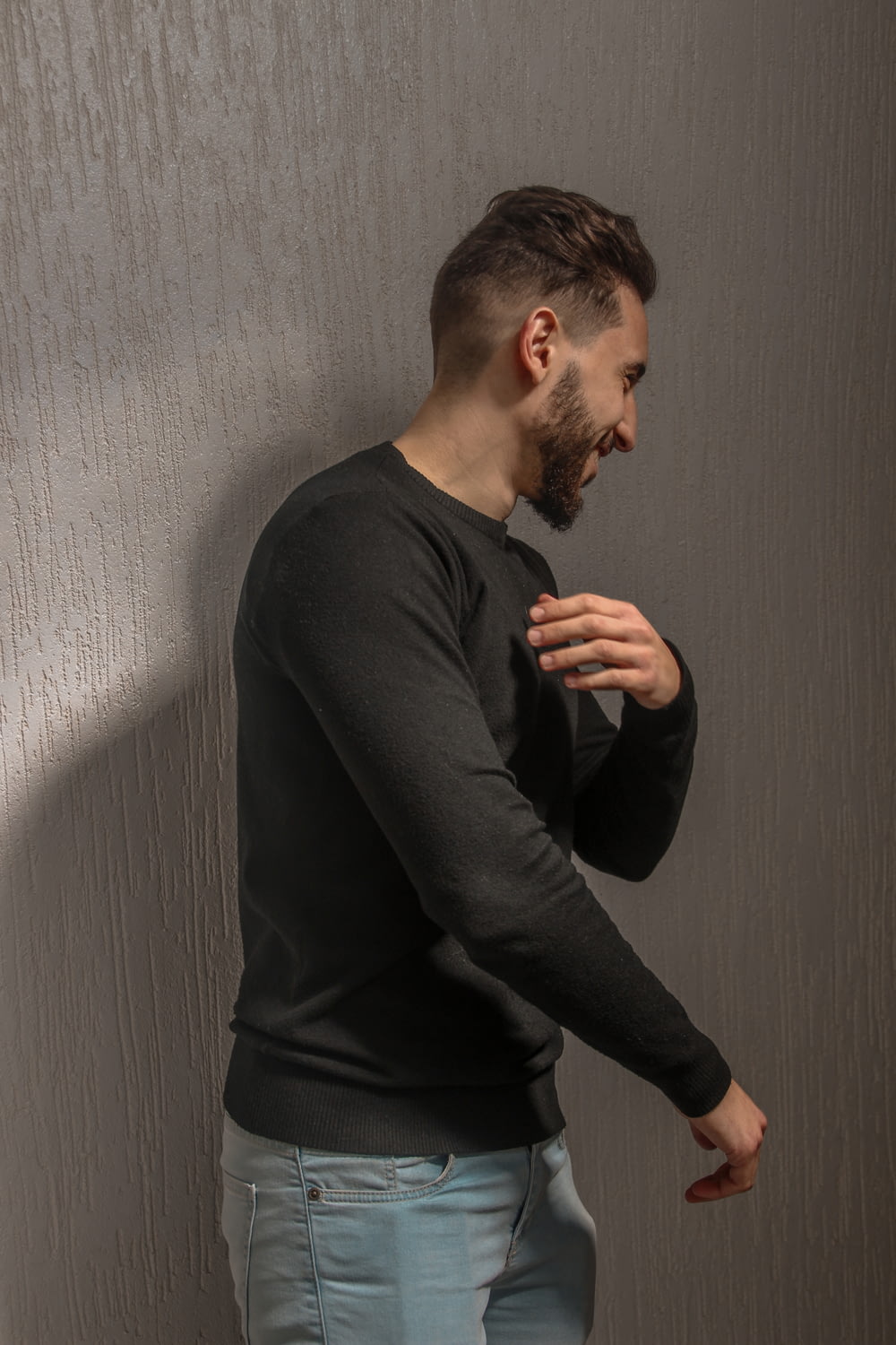 man in black long sleeve shirt standing beside white wall