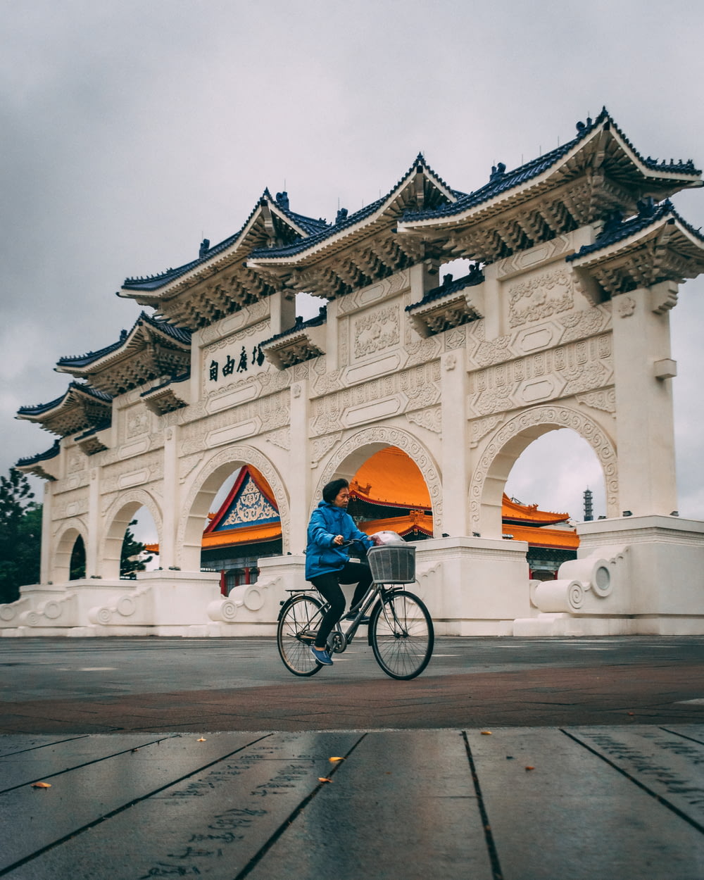 man in blue shirt riding bicycle in front of white concrete building during daytime