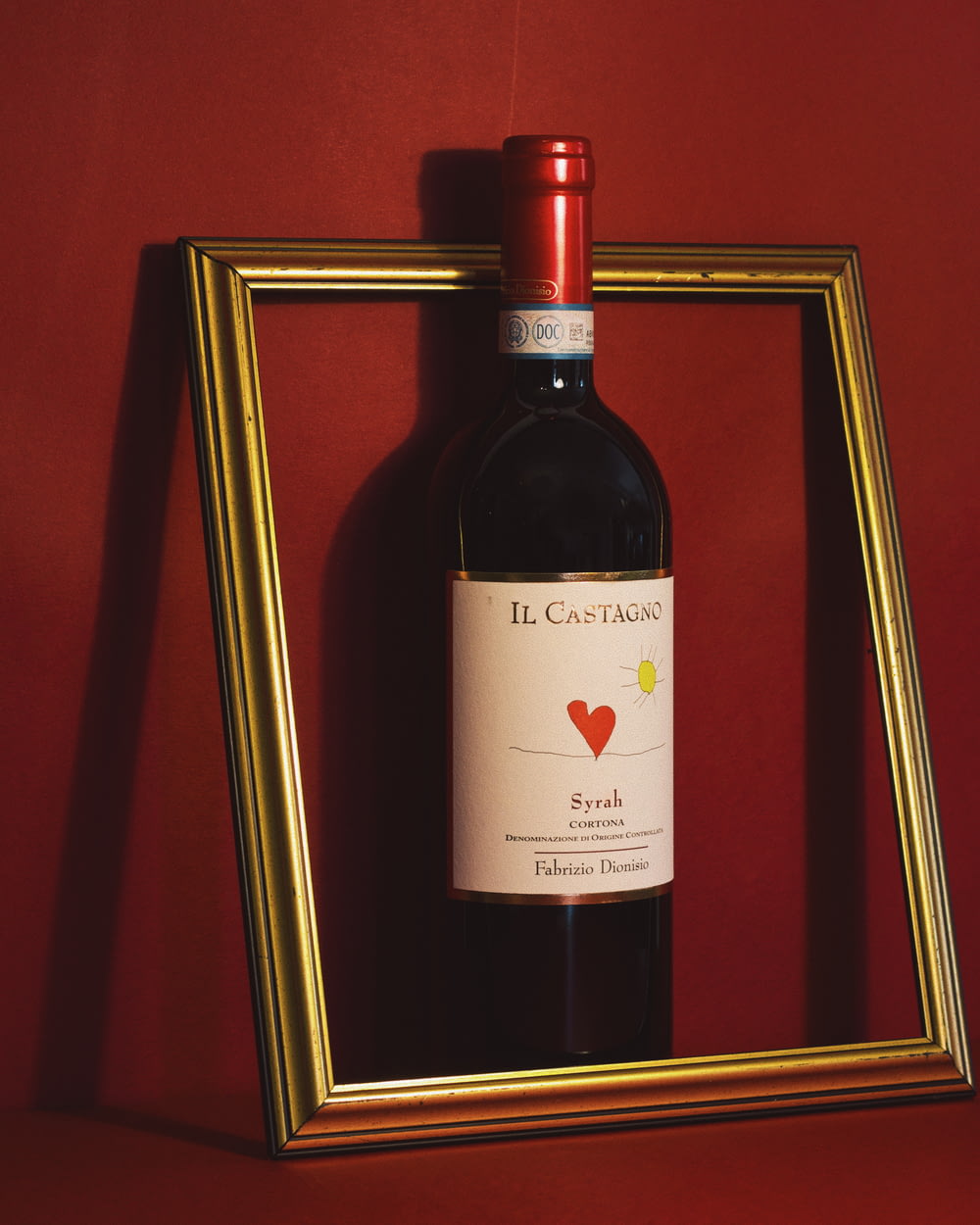 a bottle of wine sitting in front of a picture frame