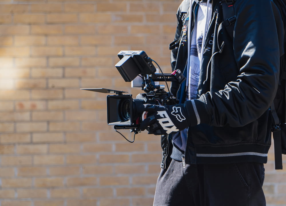 man in black jacket holding black video camera