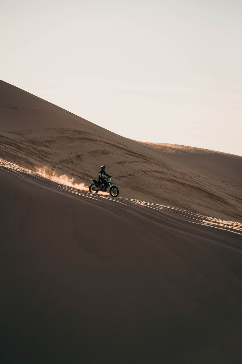 uomo che guida la moto sulla sabbia marrone
