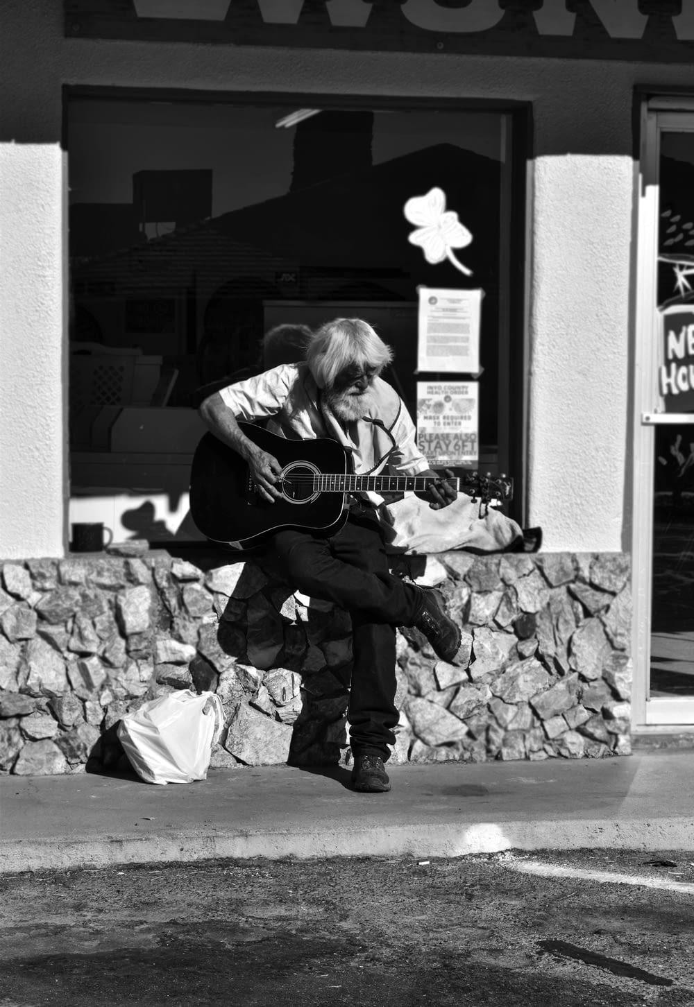 Mujer tocando la guitarra acústica en fotografía en escala de grises