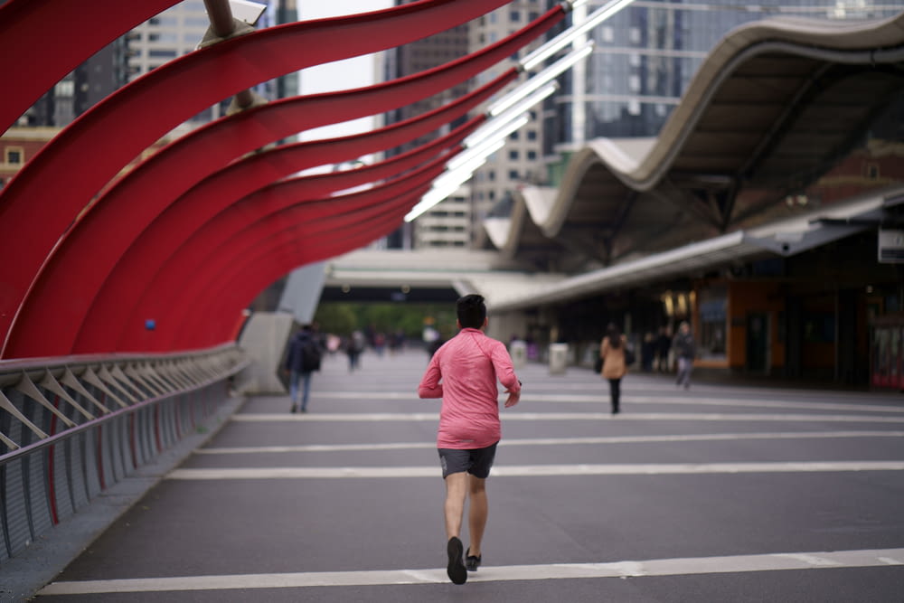 man in red t-shirt running on the bridge