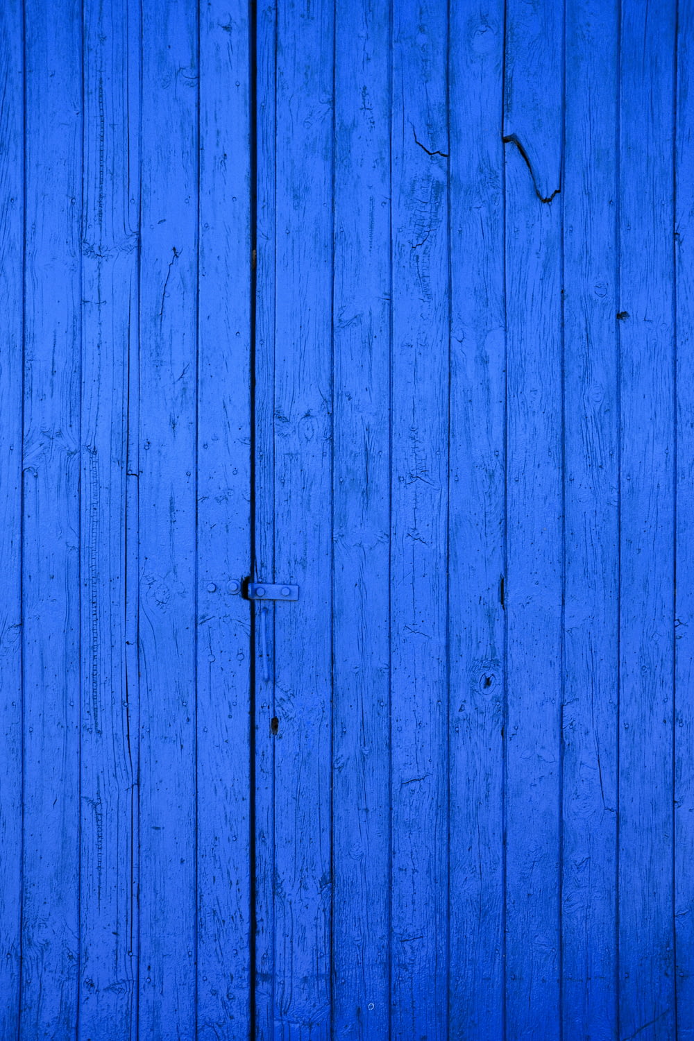 까만 금속 문 손잡이를 가진 파란 나무로 되는 문