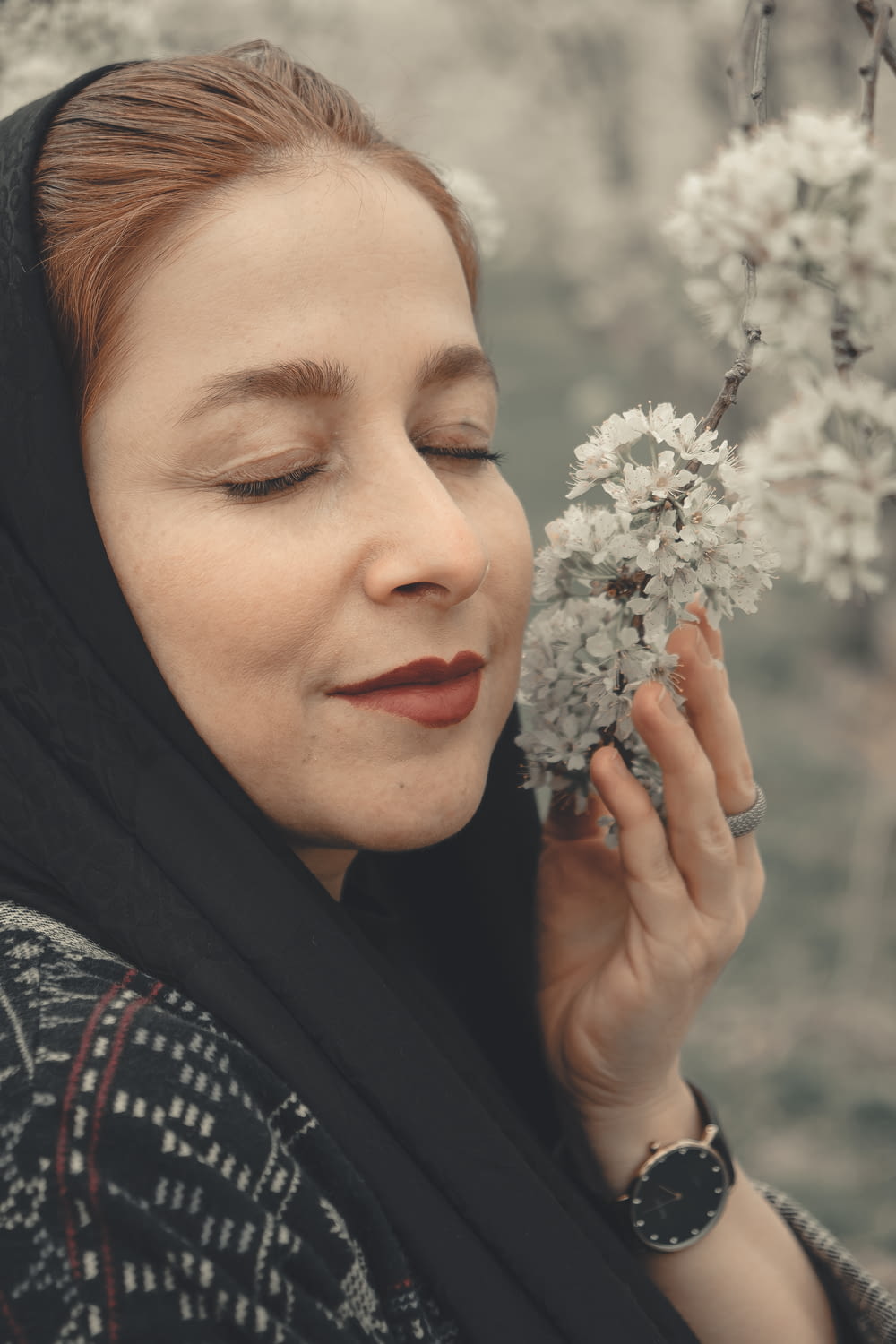 woman in black hijab holding white flowers